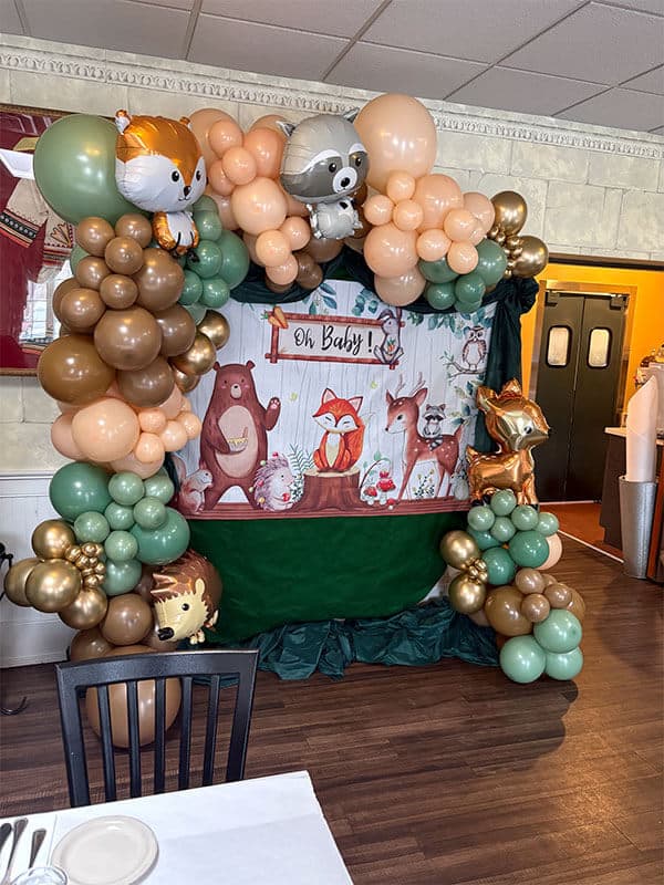 Colorful balloon arch with animal figures for a baby shower at Symeon's Greek Restaurant.